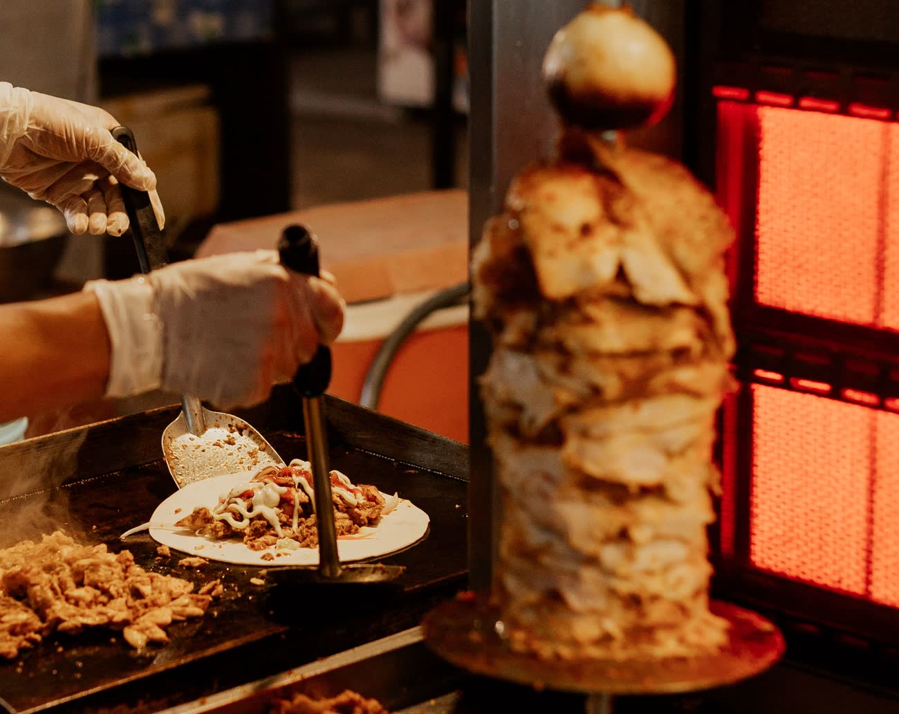 A cook plating meat carved from the vertical spit